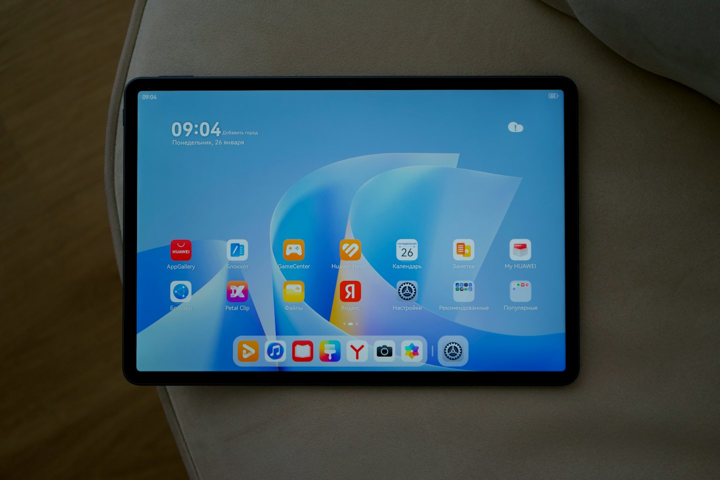 Black tablet displaying the home interface on a beige surface.