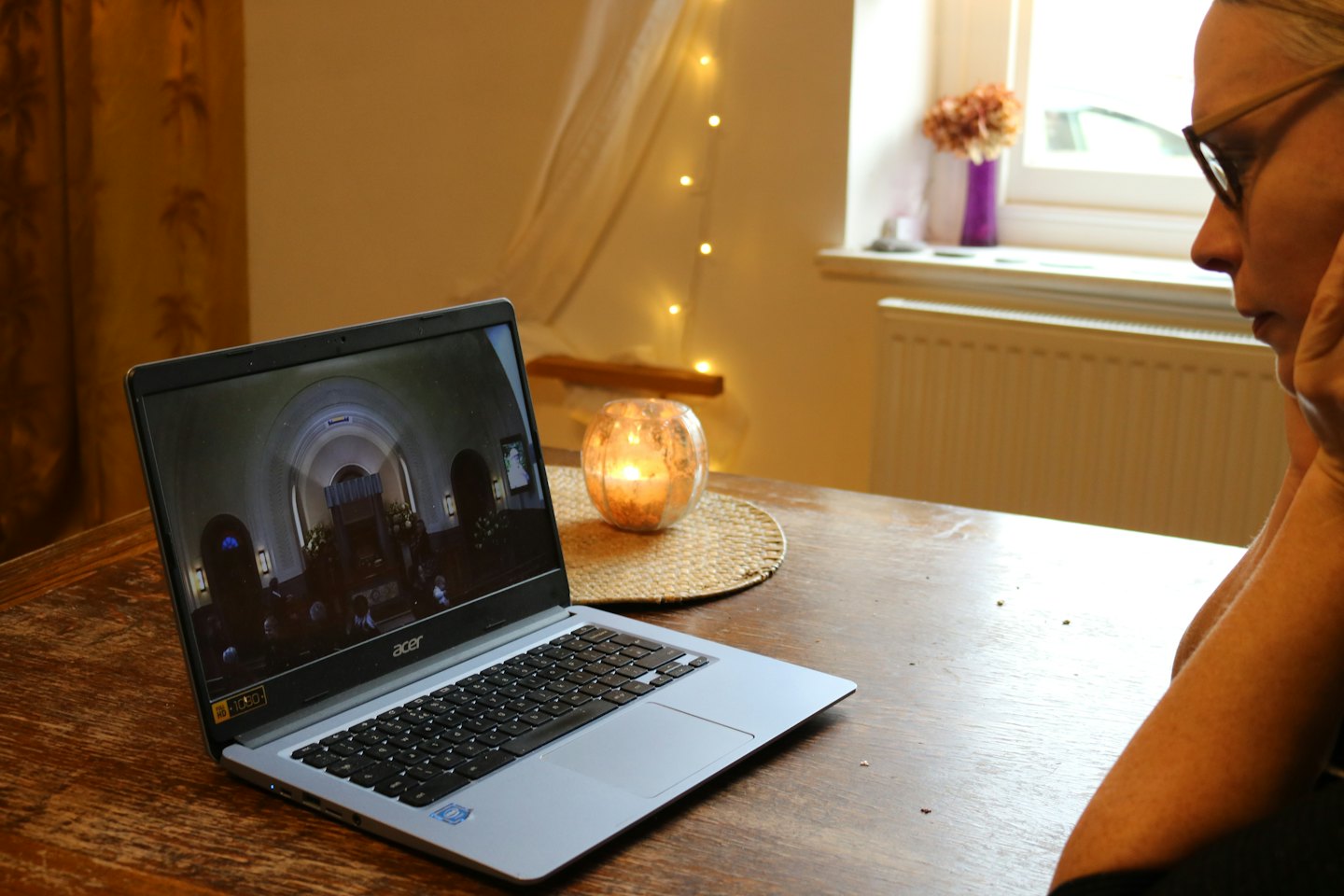 Person watches video on laptop with flickering candle.